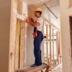 Male builder painting wall in house under construction Male builder painting wall in house under construction